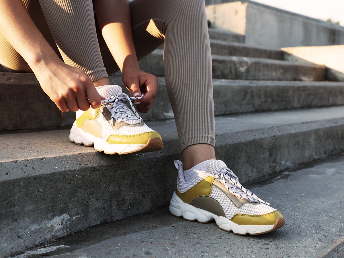 lady putting on running trainers sitting on stairs
